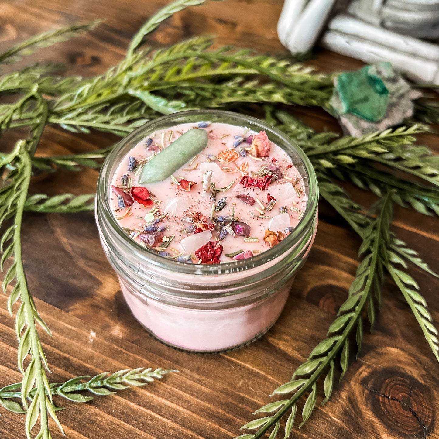 Pink intention crystal candle that is decorated with a rose charm, pink magic glitter. The candle also has crystals and herbs for manifesting beauty, love and confidence.