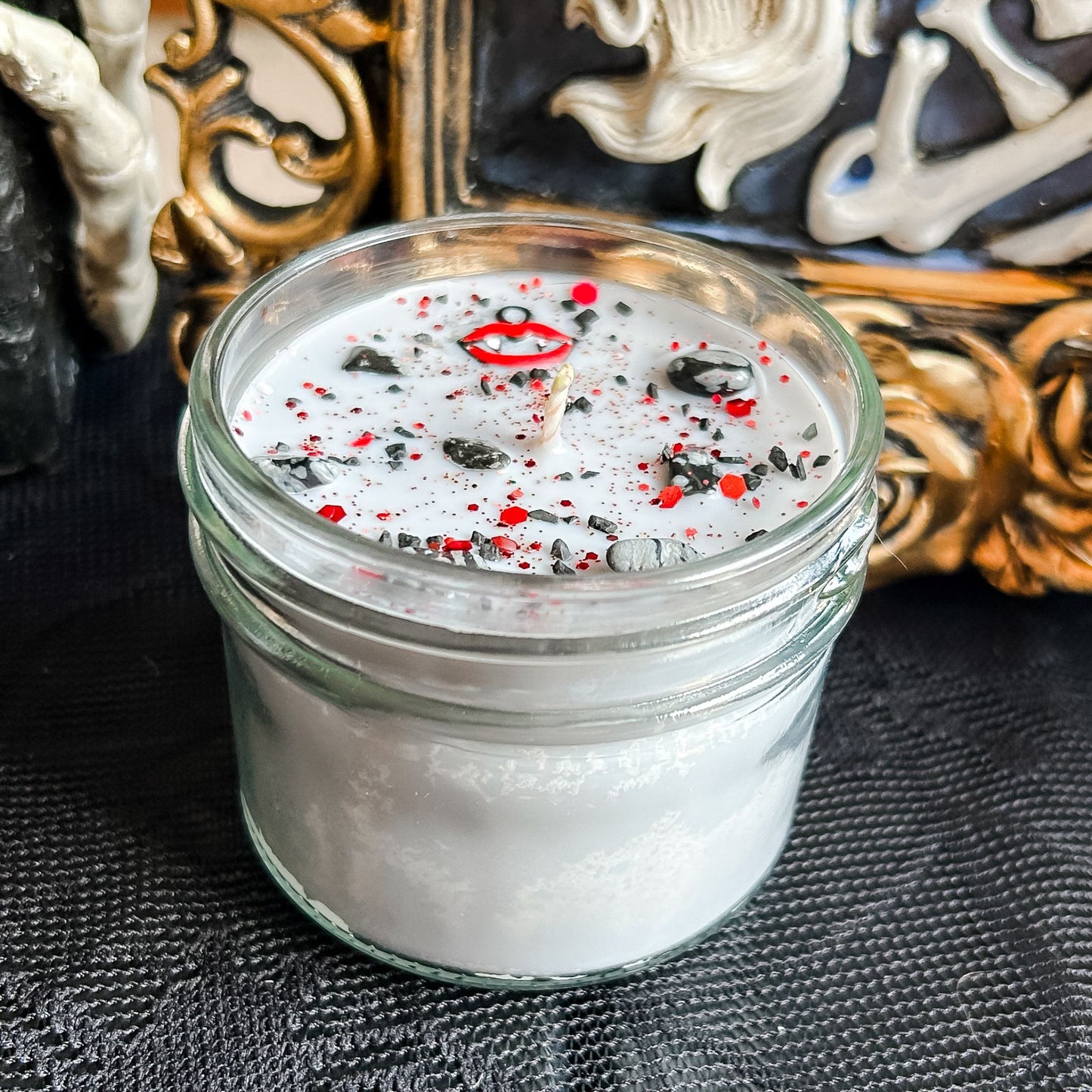 A Halloween candle with vampire fangs, gothic crystals, and spooky red glitter.