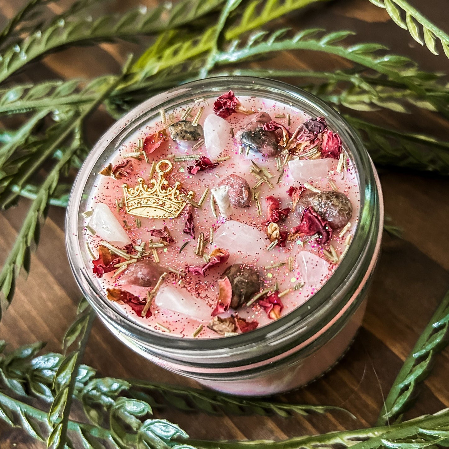 Pink intention crystal candle that is decorated with a princess crown charm, pink magic glitter. The candle also has crystals and herbs for manifesting self-love and confidence.