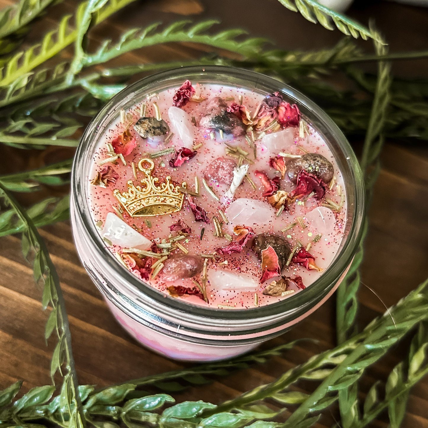 Pink intention crystal candle that is decorated with a princess crown charm, pink magic glitter. The candle also has crystals and herbs for manifesting self-love and confidence.
