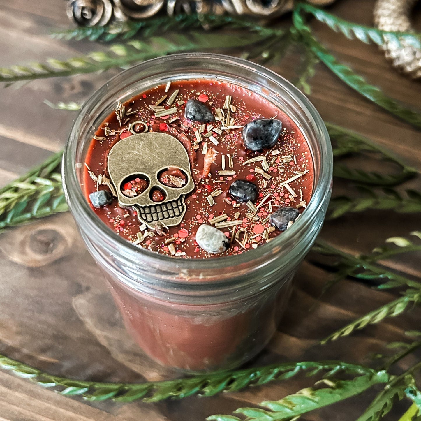 A Halloween candle that smells like campfire and is decorated with a spooky skull and gothic crystals.