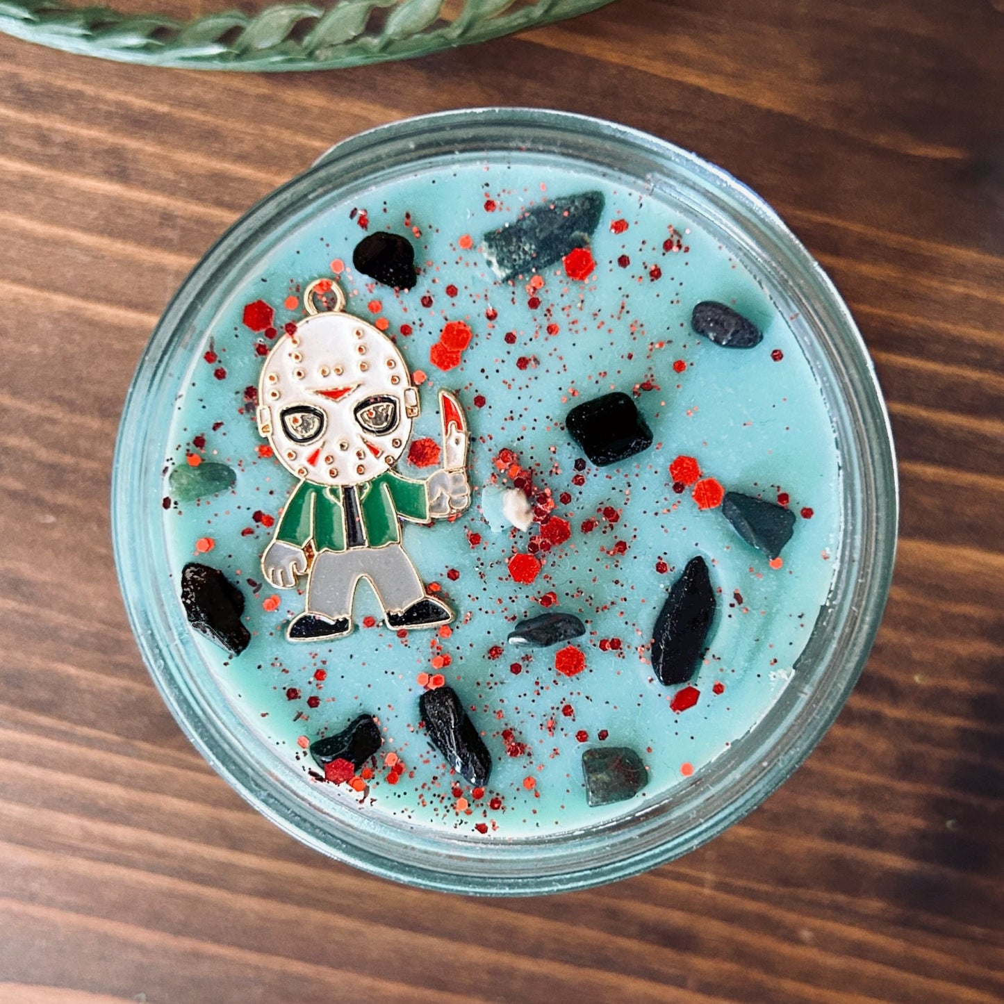 A blue Halloween candle with a Jason Voorhees horror movie charm, spooky crystals, and gothic glitter.