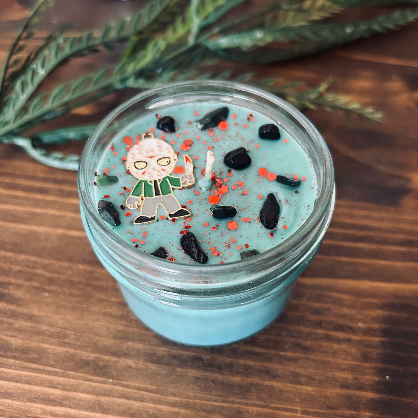 A blue Halloween candle with a Jason Voorhees horror movie charm, spooky crystals, and gothic glitter.