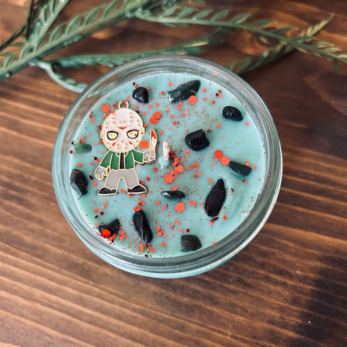 A blue Halloween candle with a Jason Voorhees horror movie charm, spooky crystals, and gothic glitter.