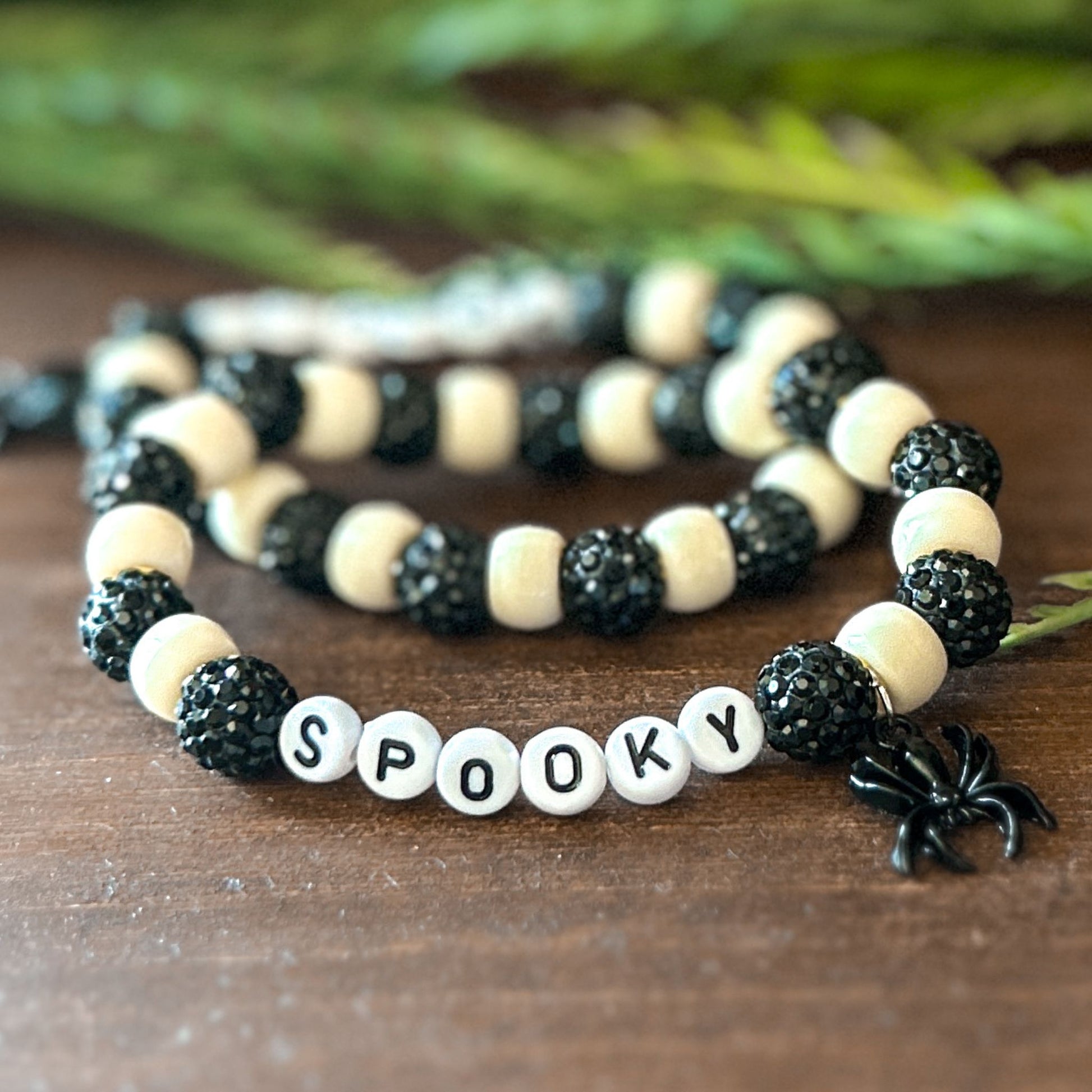 Halloween Bracelet with sparkly black and white beads with letters that say Spooky. The bracelet also has a ghost spider.