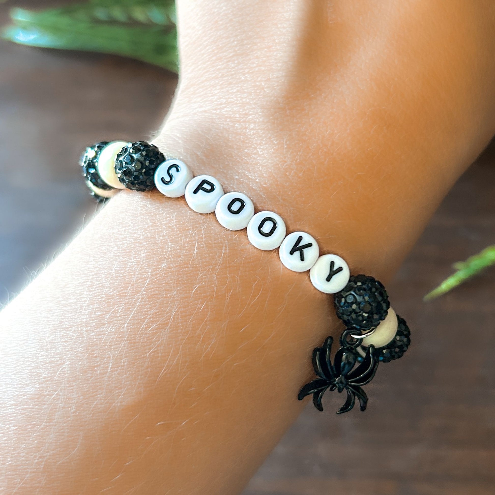 Halloween Bracelet with sparkly black and white beads with letters that say Spooky. The bracelet also has a ghost spider.