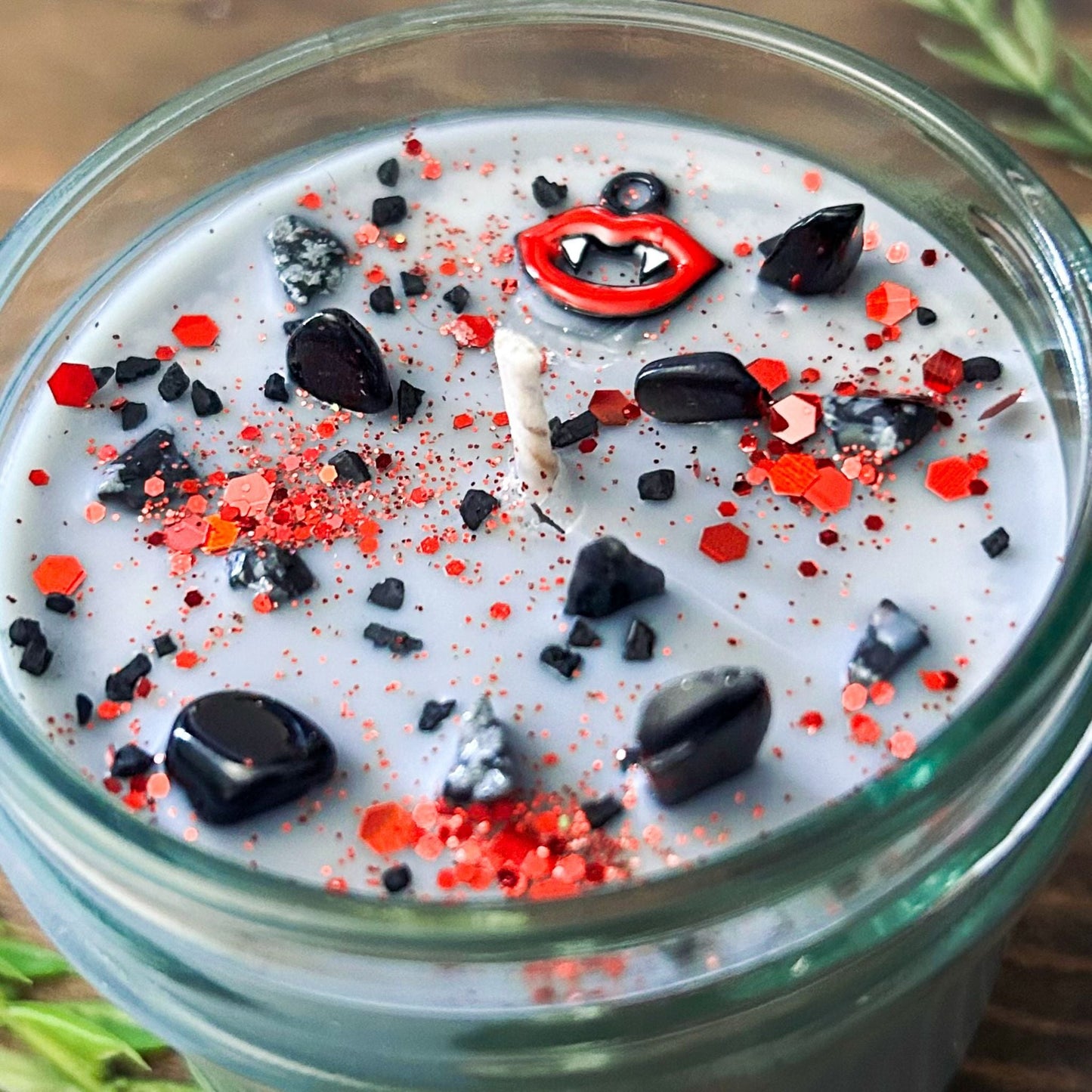 A Halloween candle with vampire fangs, gothic crystals, and spooky red glitter.