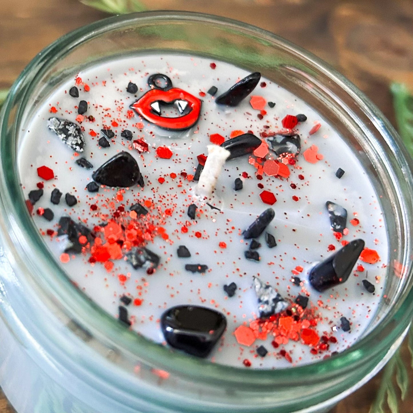 A Halloween candle with vampire fangs, gothic crystals, and spooky red glitter.