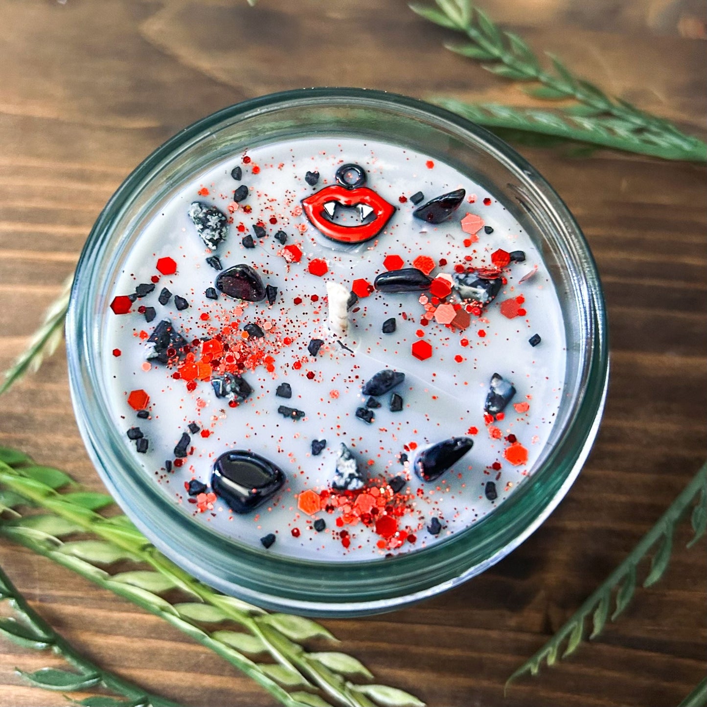 A Halloween candle with vampire fangs, gothic crystals, and spooky red glitter.