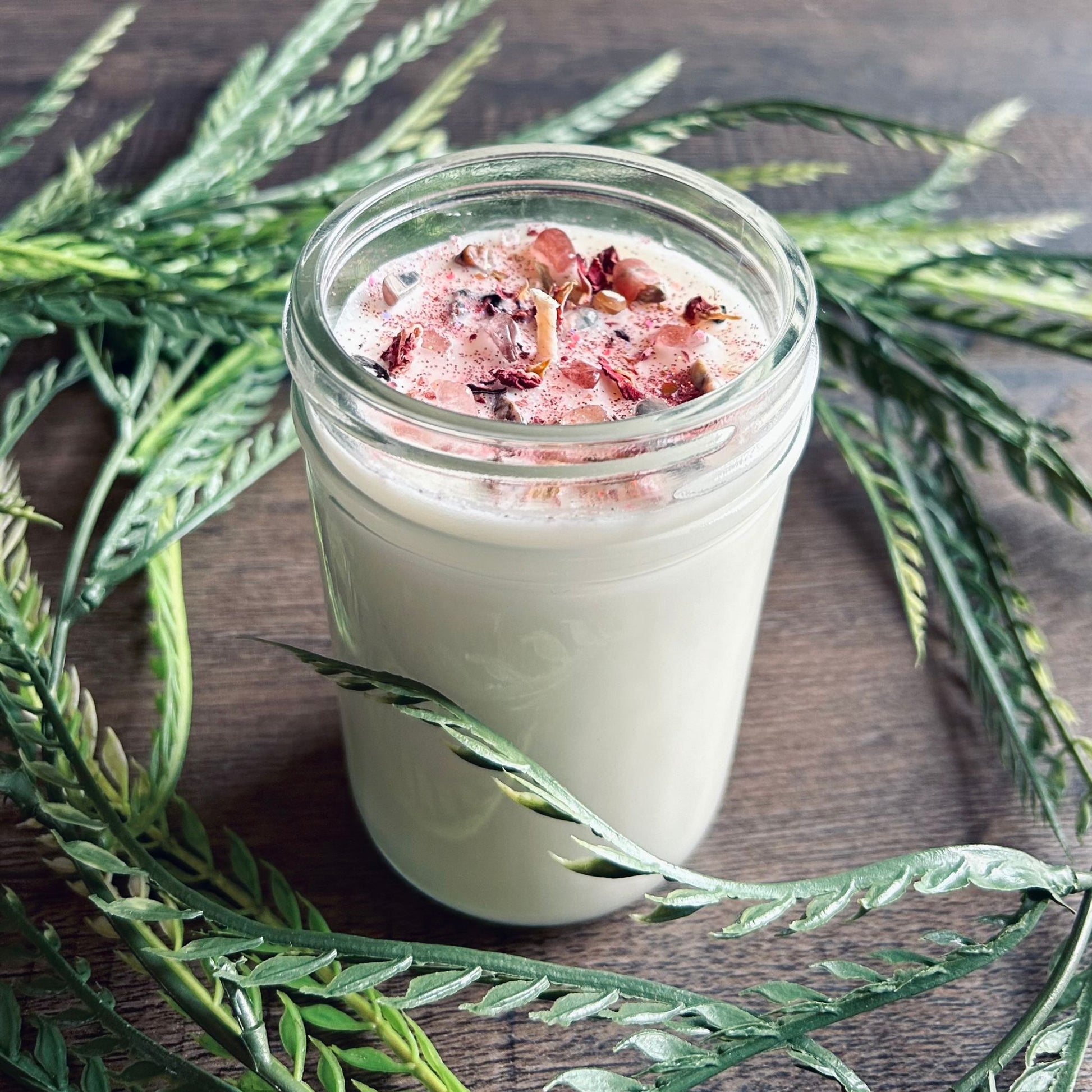 White love spell intention candle with rose quartz crystals and rose petals for love rituals and manifestation.
