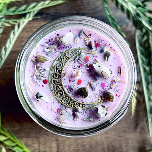 Purple intention candle that is decorated with a crescent moon and has crystals and herbs for lucid dreaming.