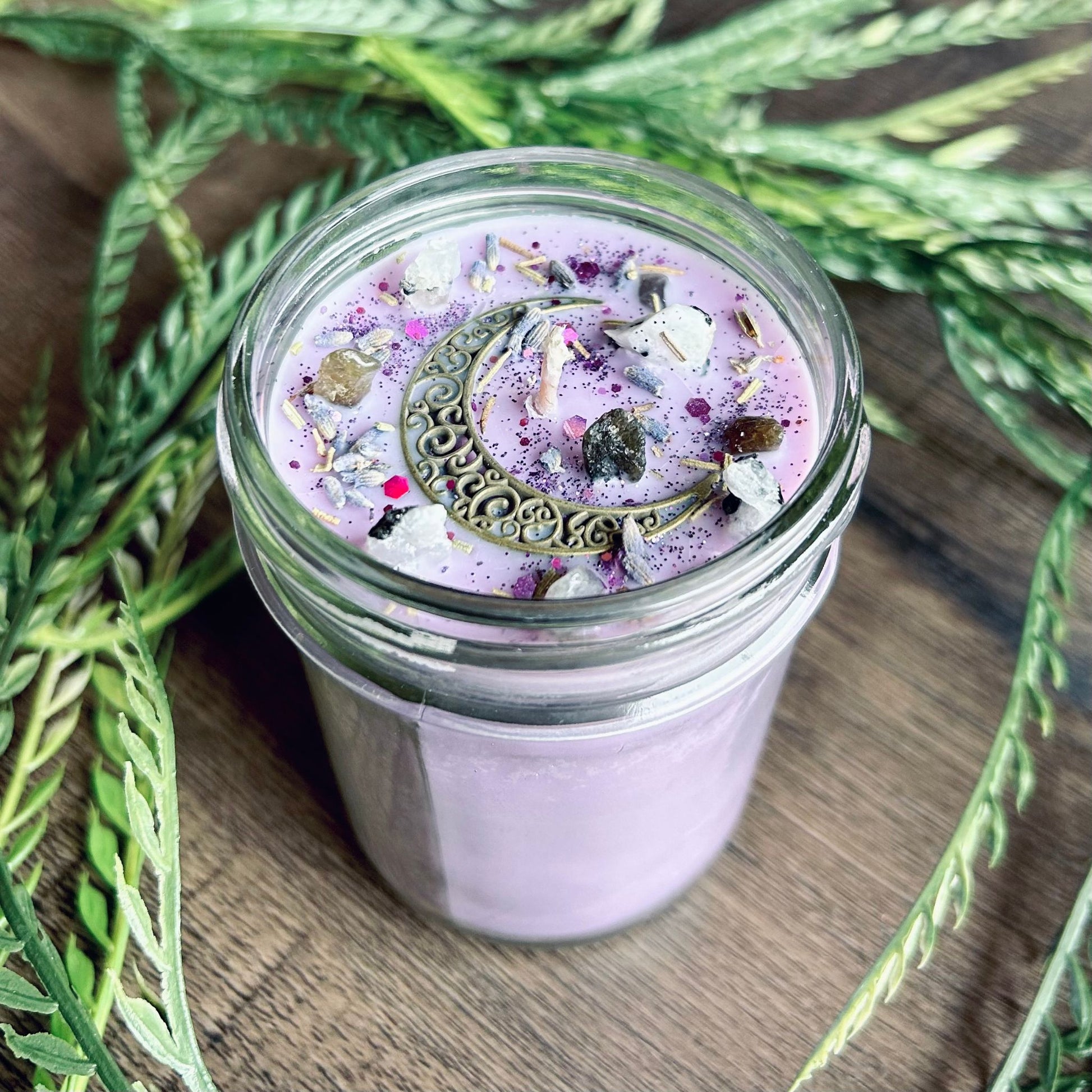 Purple intention candle that is decorated with a crescent moon and has crystals and herbs for lucid dreaming.
