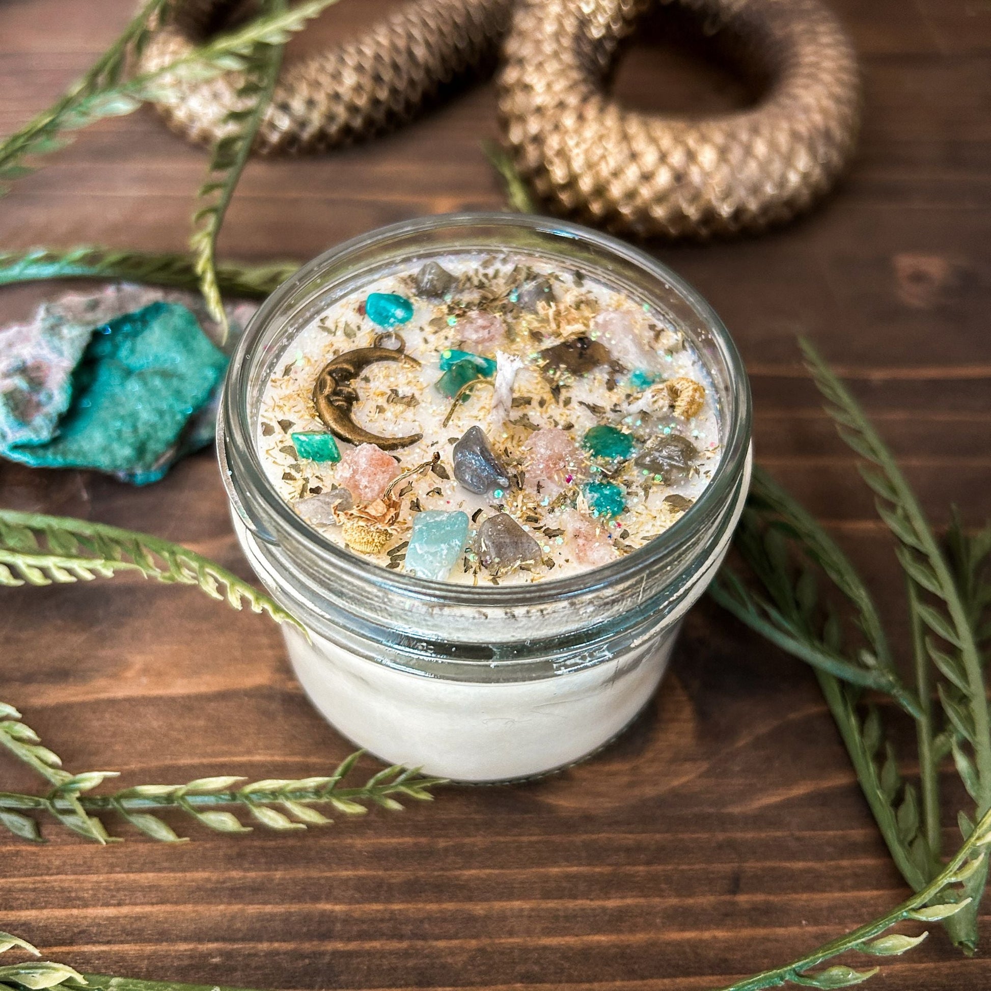 White intention candle that is decorated with a mystical crescent moon. The candle also has crystals, herbs, and magic glitter for setting intentions for new beginnings and fresh starts.