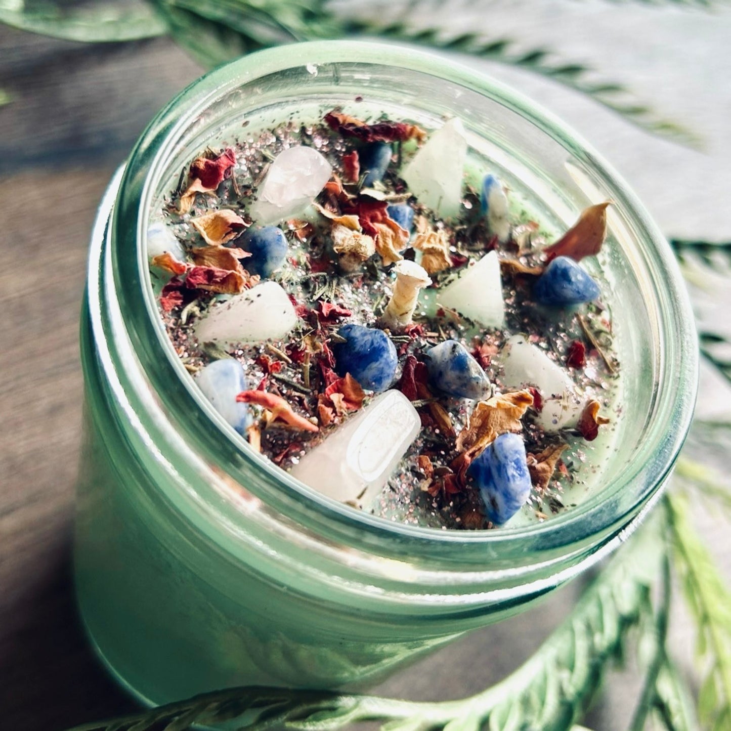 Light green intention pagan candle that is decorated with crystals, flowers, and magic glitter to manifest rituals for the spring equinox, rebirth, fertility, and renewal