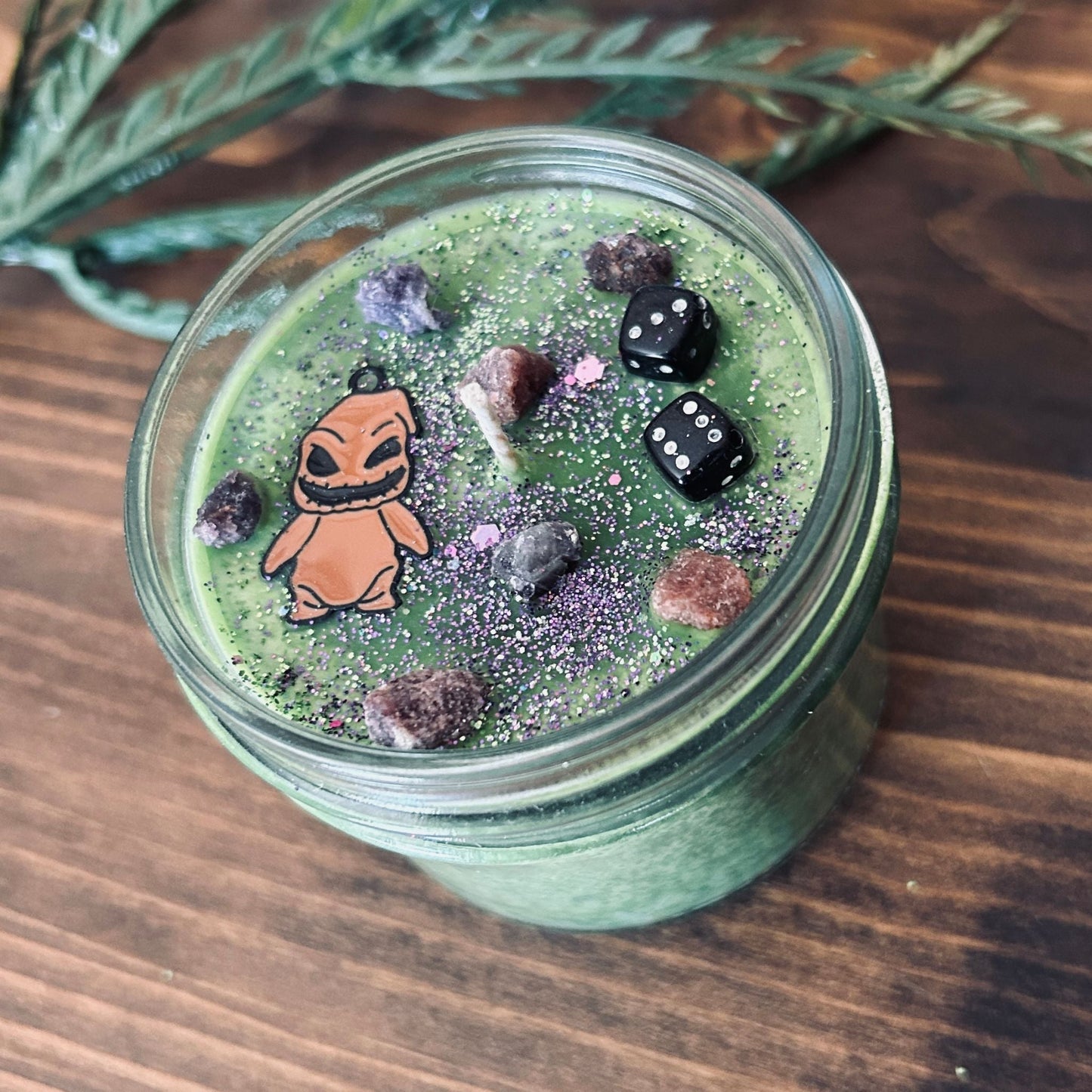 A Halloween candle that is decorated with a nightmare before Christmas oogie boogie, spooky crystals, and gothic glitter.