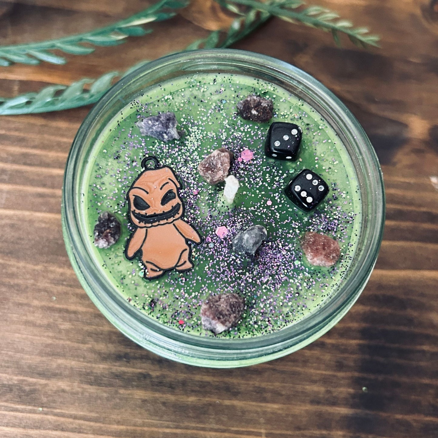 A Halloween candle that is decorated with a nightmare before Christmas oogie boogie, spooky crystals, and gothic glitter.