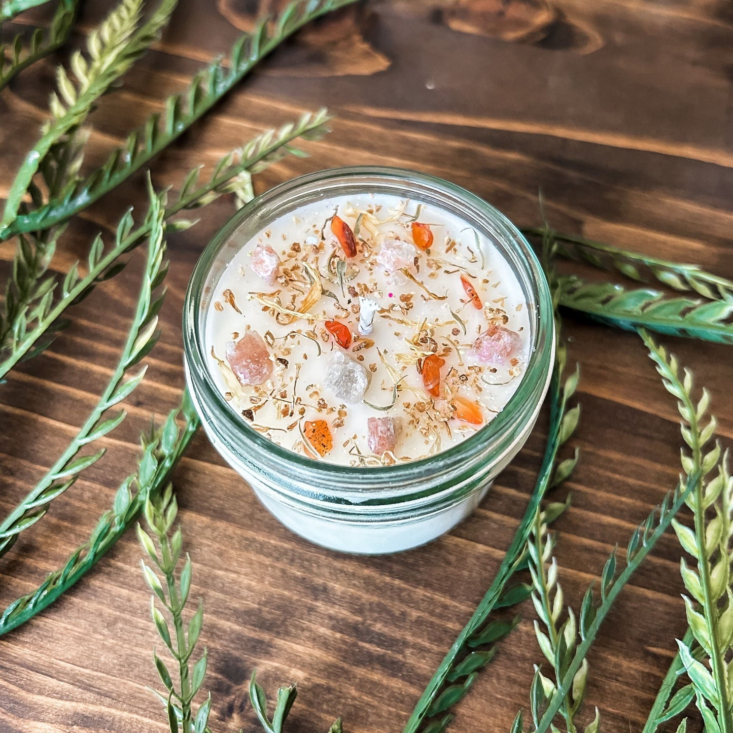 White crystal intention candle that is decorated with witchy crystals, herbs, and glitter for positive energy, healing energy, and cleansing.