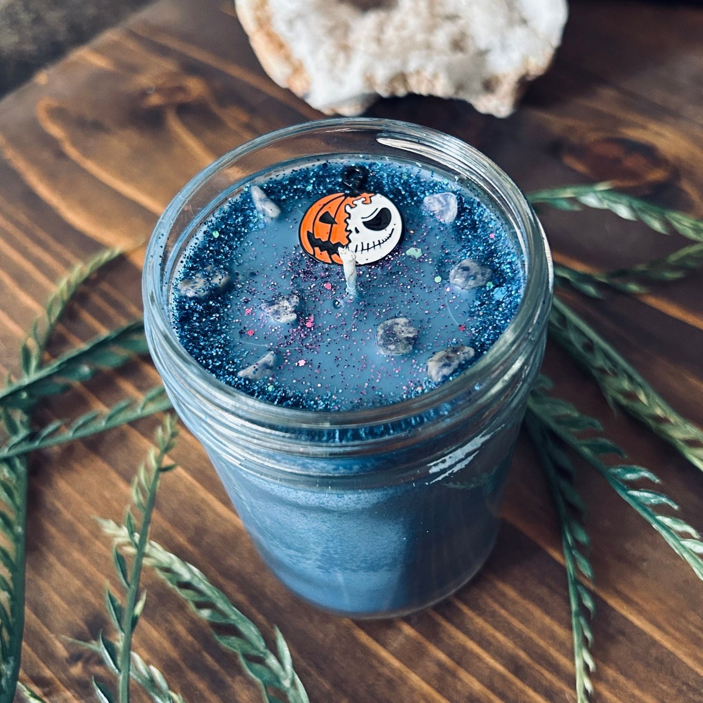 A blue Halloween candle that is decorated with a nightmare before Christmas Jack Skellington, spooky crystals, and creepy glitter.
