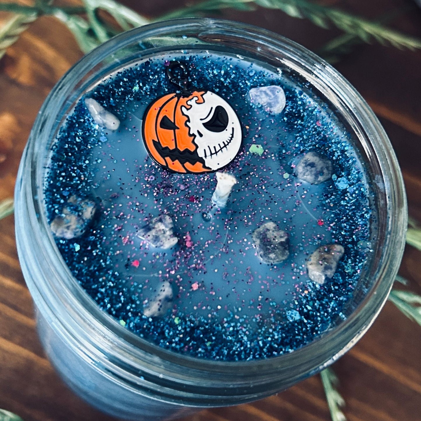 A blue Halloween candle that is decorated with a nightmare before Christmas Jack Skellington, spooky crystals, and creepy glitter.