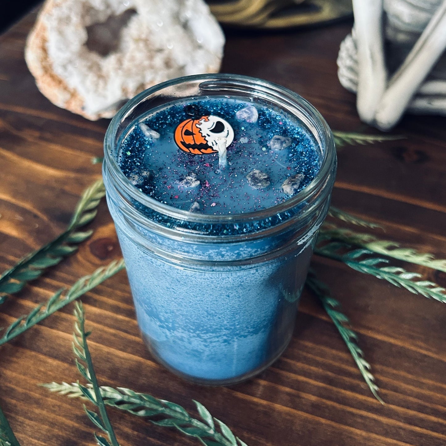 A blue Halloween candle that is decorated with a nightmare before Christmas Jack Skellington, spooky crystals, and creepy glitter.