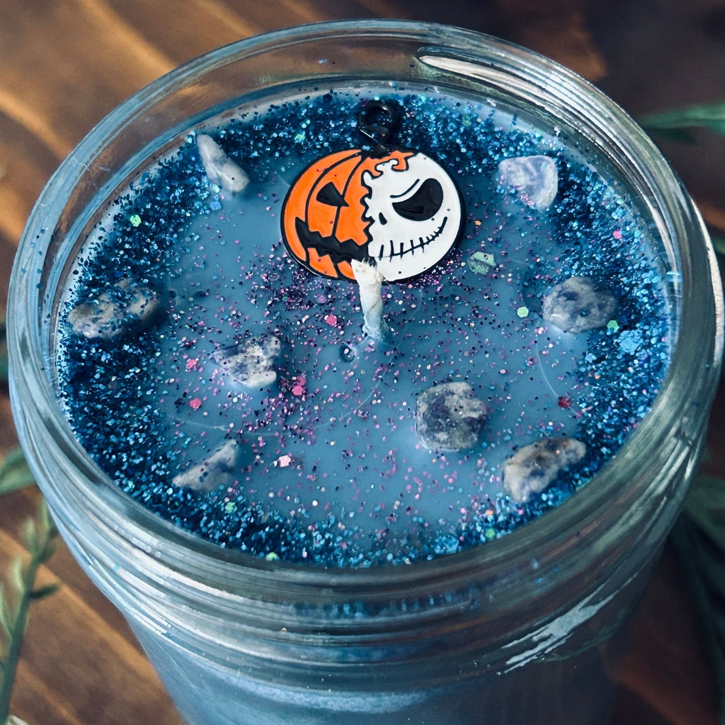 A blue Halloween candle that is decorated with a nightmare before Christmas Jack Skellington, spooky crystals, and creepy glitter.