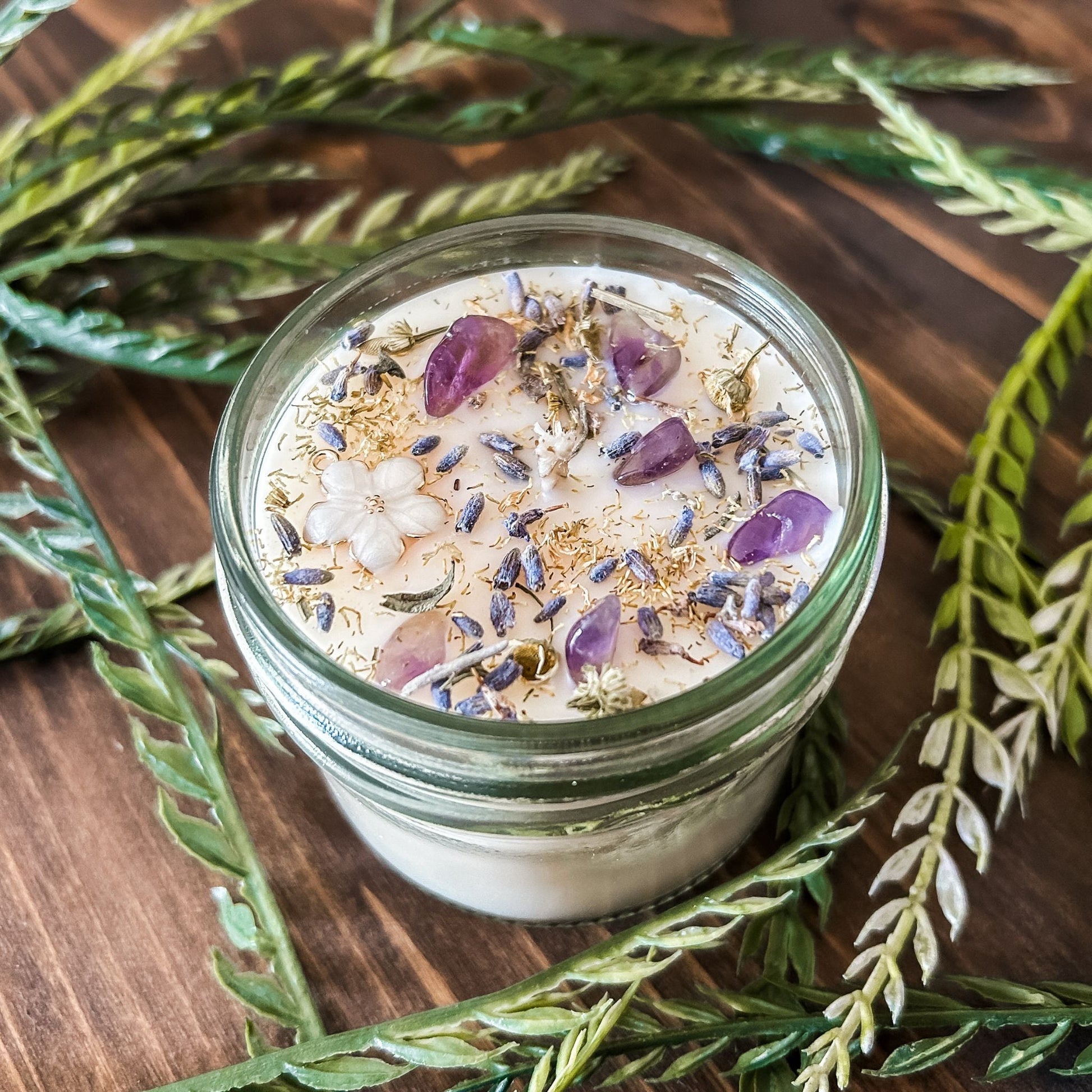 Natural soy intention candle that is decorated with a white flower, amethyst crystals. lavender, chamomile, and glitter for healing, anxiety relief, and calm energy.