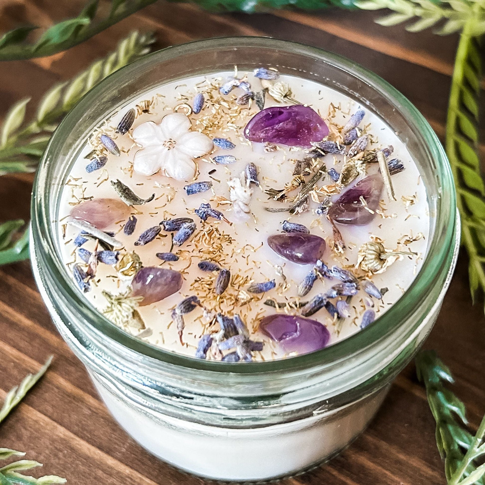 Natural soy intention candle that is decorated with a white flower, amethyst crystals. lavender, chamomile, and glitter for healing, anxiety relief, and calm energy.