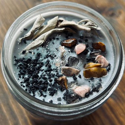 Silver intention candle that is decorated with gold tigers eye crystal, smokey quartz crystal, rhodonite crystal, protection salt, white sage, and witchy glitter to manifest goddess energy and power.