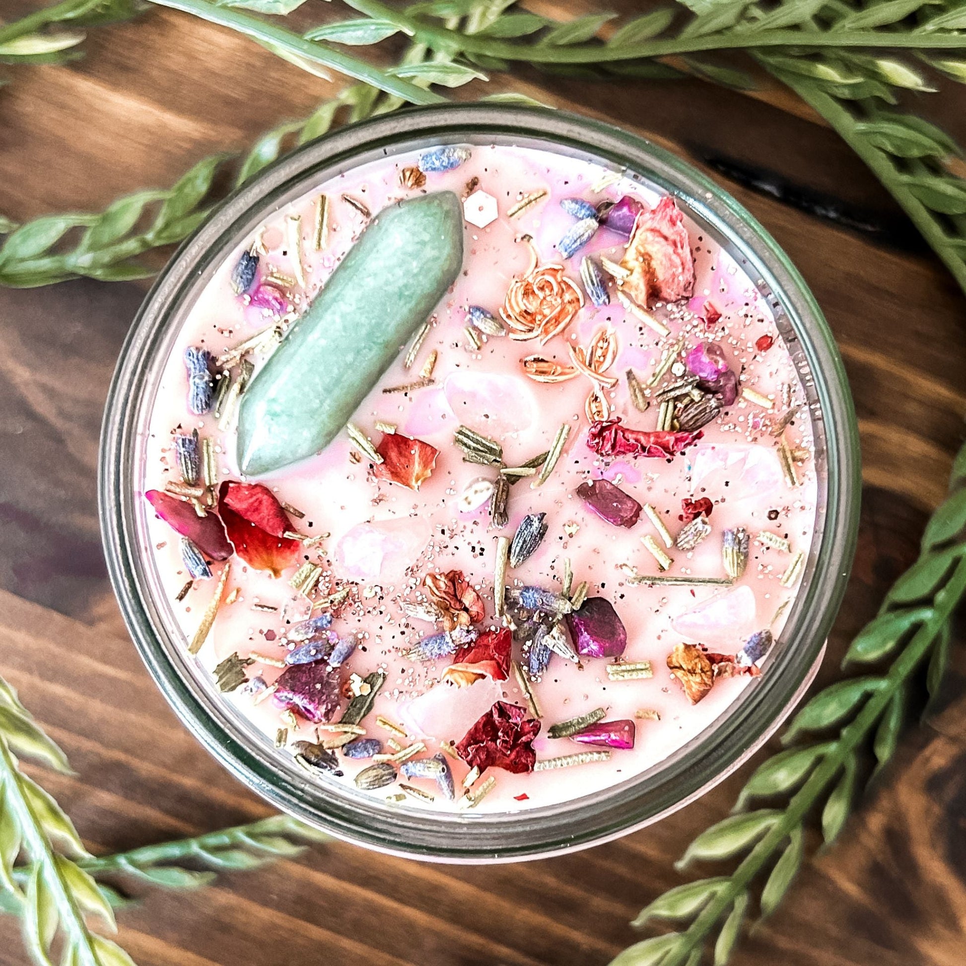 Pink intention crystal candle that is decorated with a rose charm, pink magic glitter. The candle also has crystals and herbs for manifesting beauty, love and confidence.