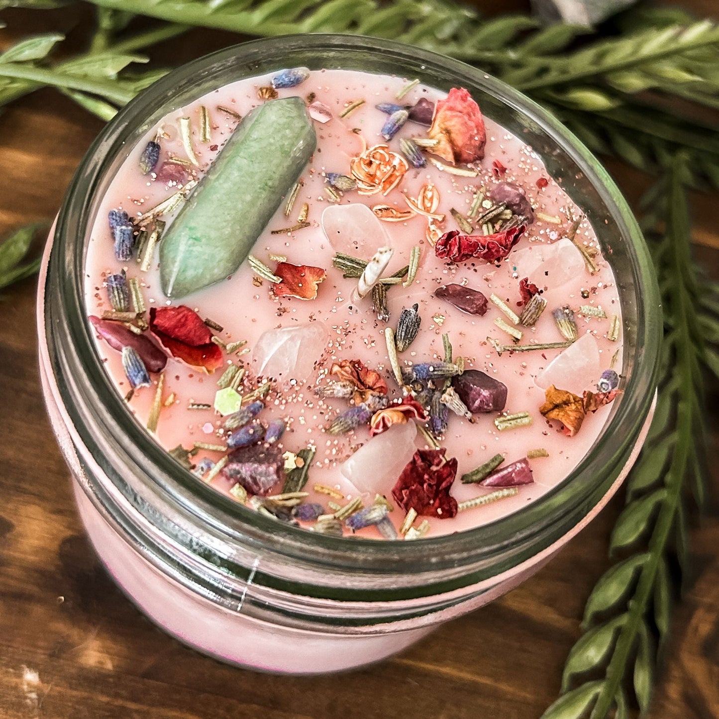Pink intention crystal candle that is decorated with a rose charm, pink magic glitter. The candle also has crystals and herbs for manifesting beauty, love and confidence.