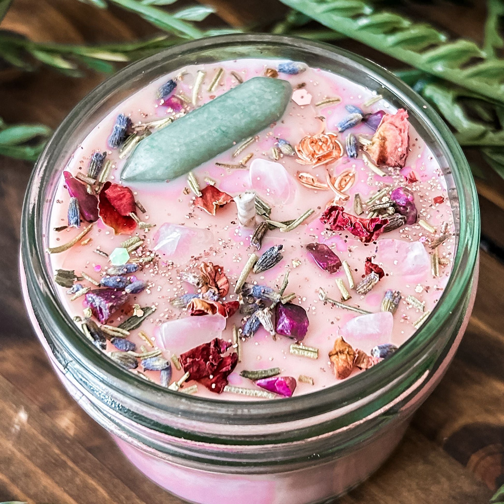 Pink intention crystal candle that is decorated with a rose charm, pink magic glitter. The candle also has crystals and herbs for manifesting beauty, love and confidence.