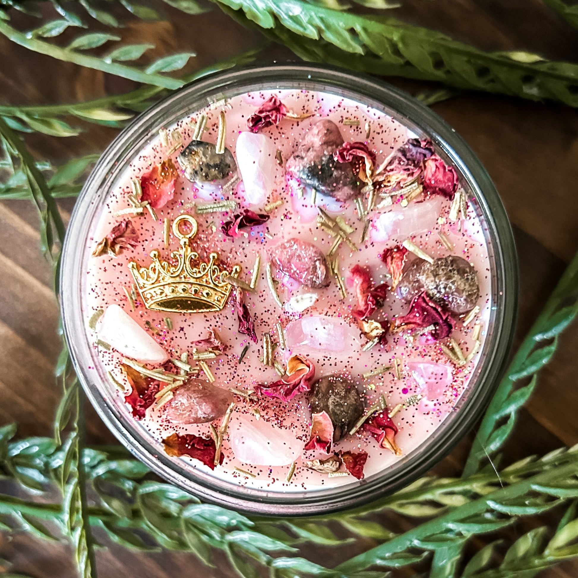 Pink intention crystal candle that is decorated with a princess crown charm, pink magic glitter. The candle also has crystals and herbs for manifesting self-love and confidence.