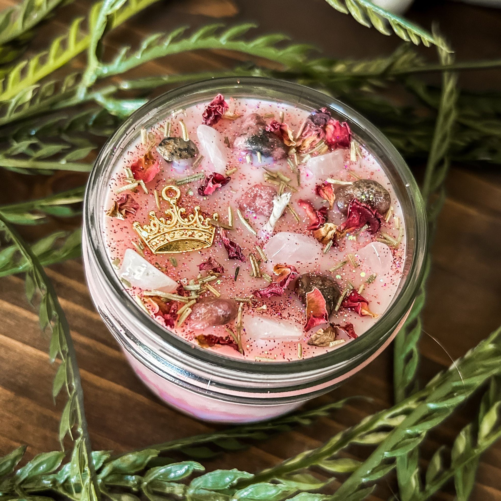 Pink intention crystal candle that is decorated with a princess crown charm, pink magic glitter. The candle also has crystals and herbs for manifesting self-love and confidence.