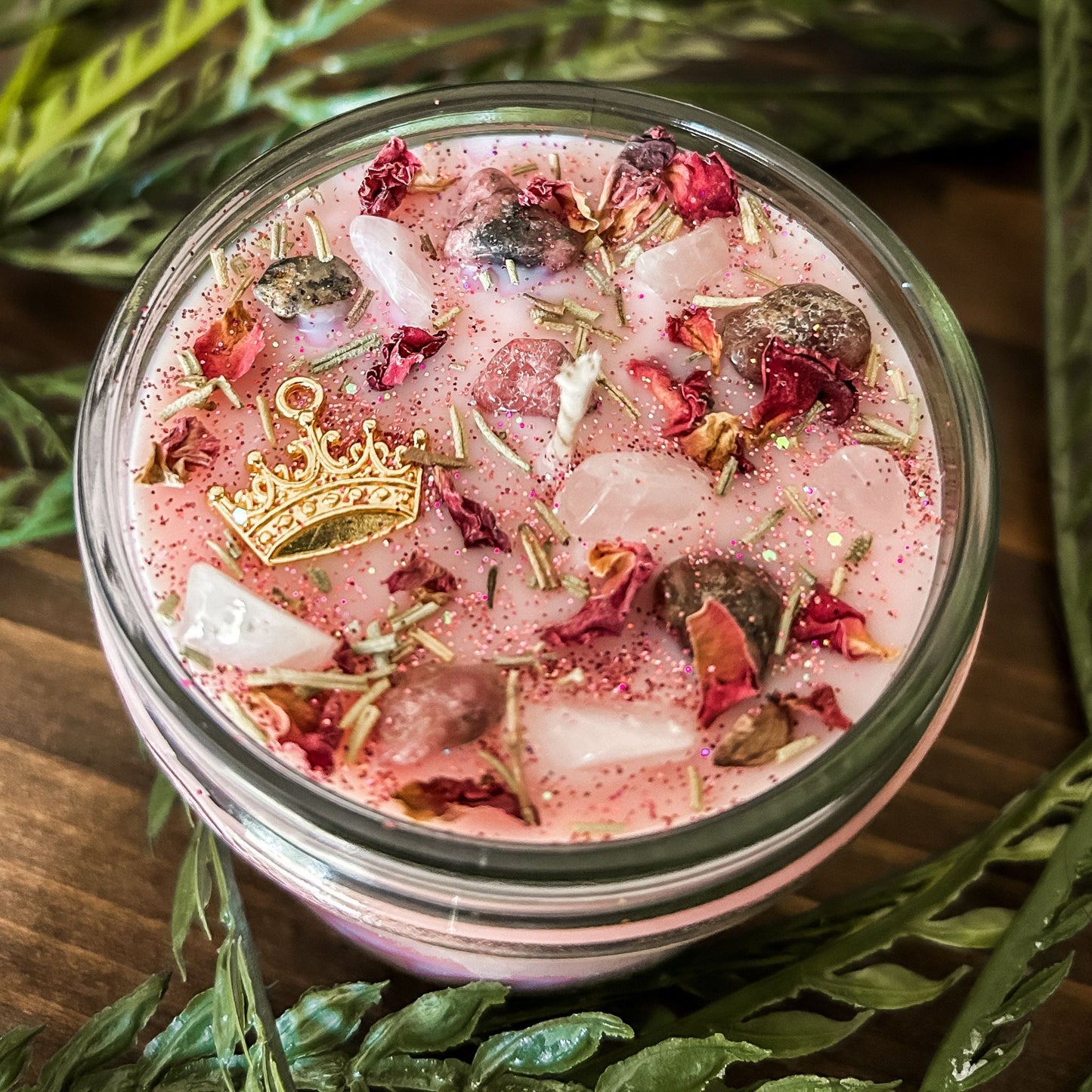 Pink intention crystal candle that is decorated with a princess crown charm, pink magic glitter. The candle also has crystals and herbs for manifesting self-love and confidence.