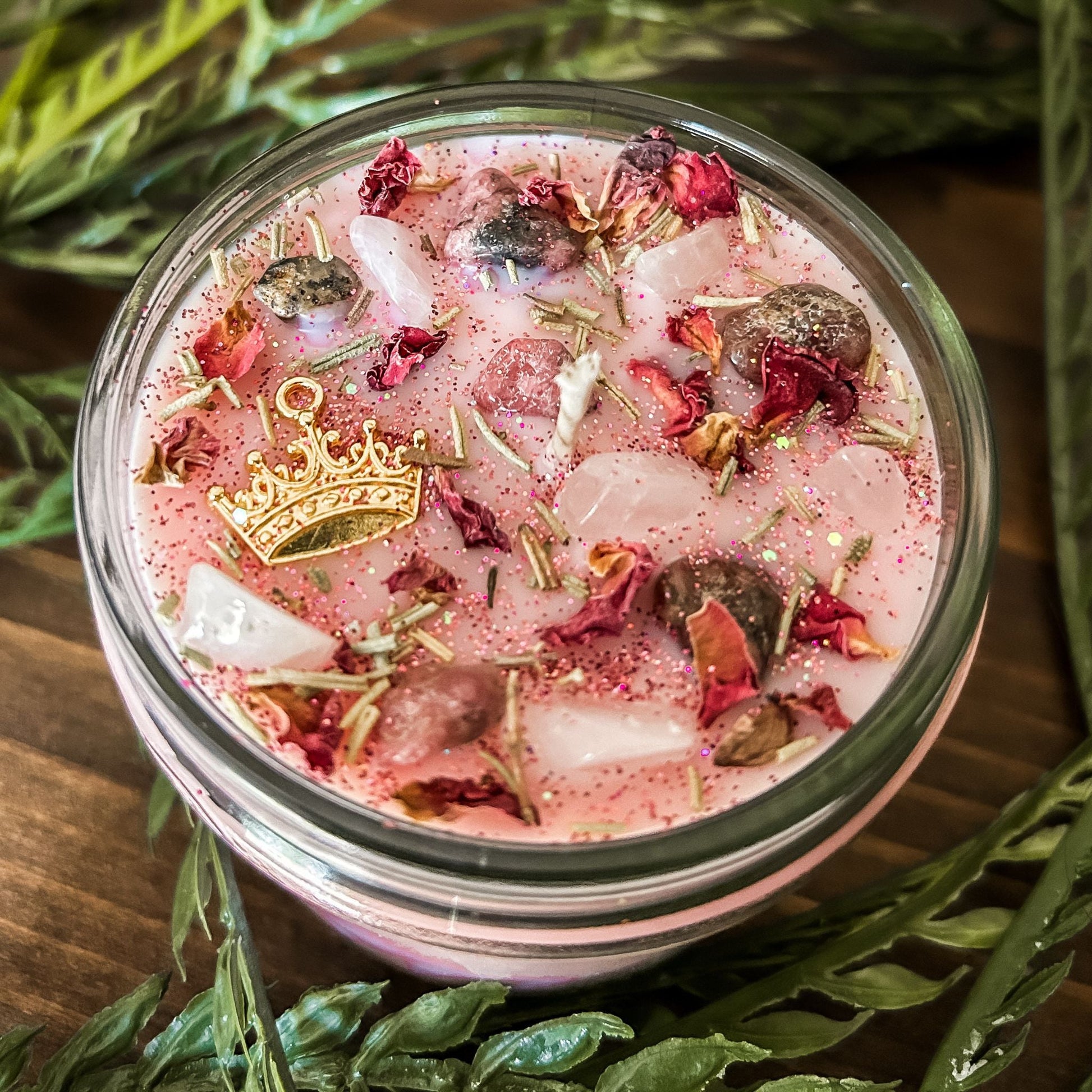 Pink intention crystal candle that is decorated with a princess crown charm, pink magic glitter. The candle also has crystals and herbs for manifesting self-love and confidence.