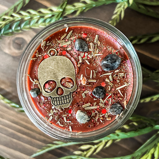 A Halloween candle that smells like campfire and is decorated with a spooky skull and gothic crystals.