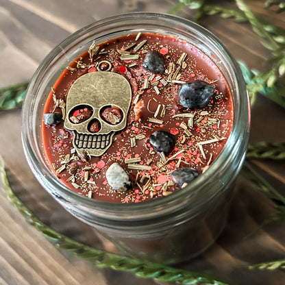 A Halloween candle that smells like campfire and is decorated with a spooky skull and gothic crystals.