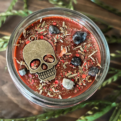 A Halloween candle that smells like campfire and is decorated with a spooky skull and gothic crystals.