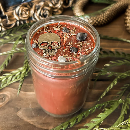 A Halloween candle that smells like campfire and is decorated with a spooky skull and gothic crystals.