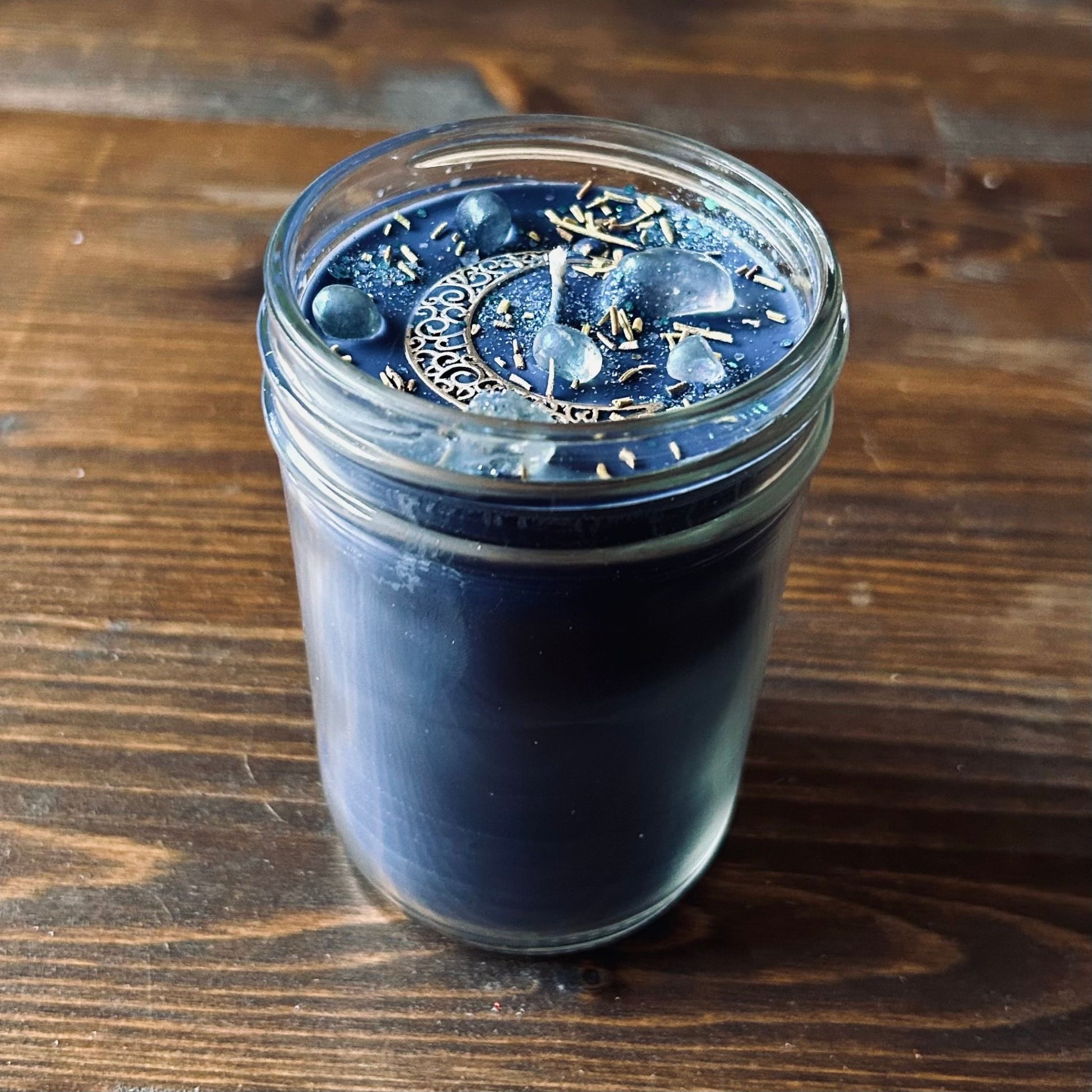 Celestial moon magic ritual candle with crystals, herbs, and a crescent moon.