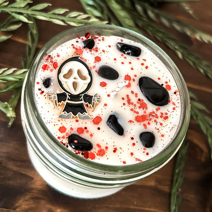 A Halloween candle decorated with a horror movie charm, spooky crystals, and gothic glitter.