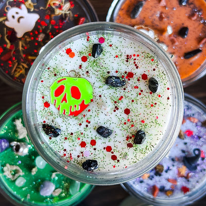 A Halloween candle decorated with a spooky melting apple charm, witchy crystals, and gothic glitter.