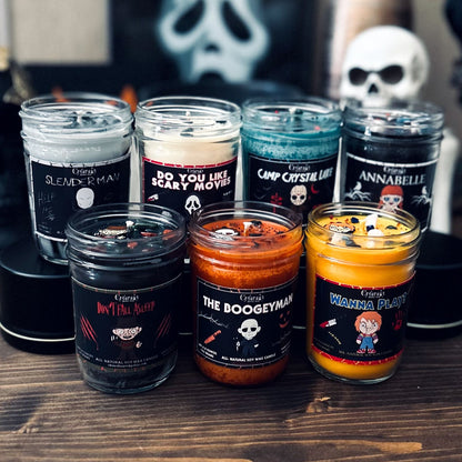 Halloween candles that are decorated with a horror movie character charm, spooky crystals, and gothic glitter.