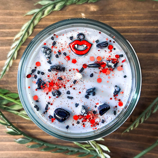 A Halloween candle with vampire fangs, gothic crystals, and spooky red glitter.