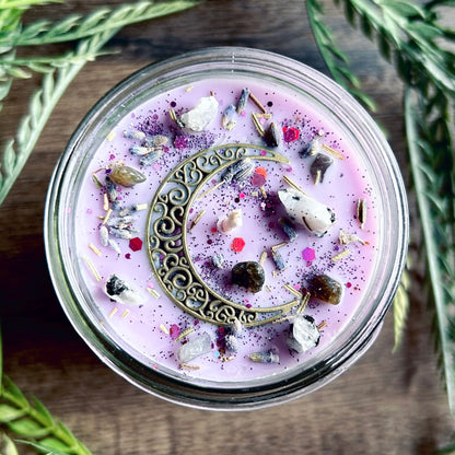 Purple intention candle that is decorated with a crescent moon and has crystals and herbs for lucid dreaming.