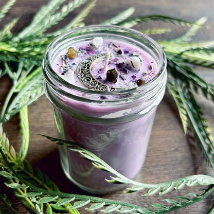 Purple intention candle that is decorated with a crescent moon and has crystals and herbs for lucid dreaming.