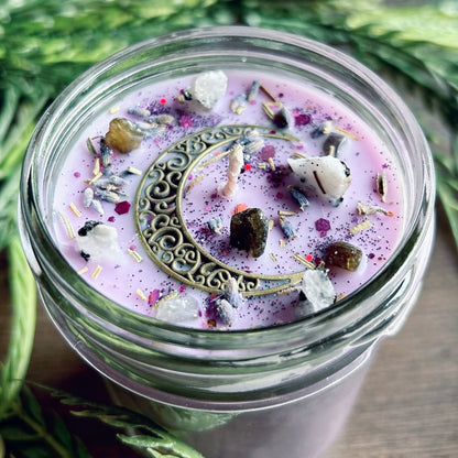 Purple intention candle that is decorated with a crescent moon and has crystals and herbs for lucid dreaming.