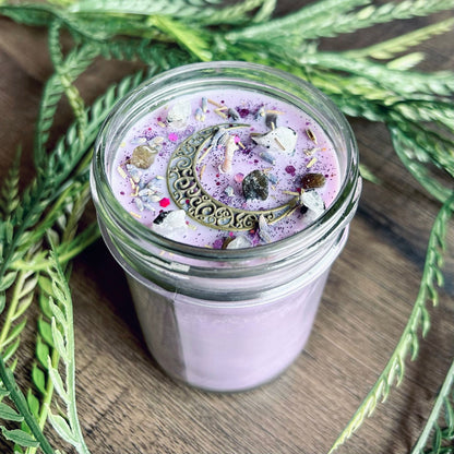 Purple intention candle that is decorated with a crescent moon and has crystals and herbs for lucid dreaming.