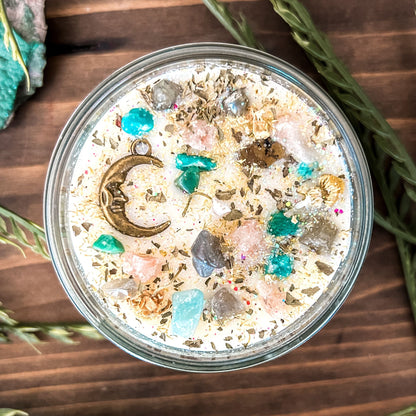 White intention candle that is decorated with a mystical crescent moon. The candle also has crystals, herbs, and magic glitter for setting intentions for new beginnings and fresh starts.