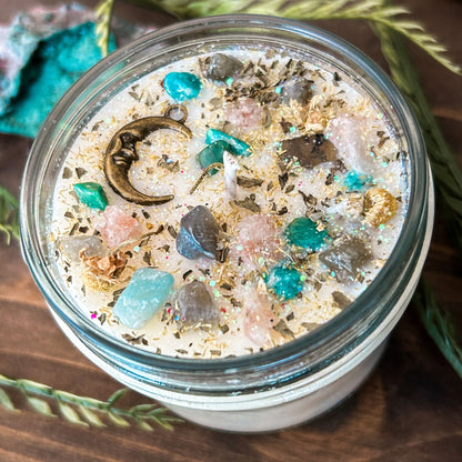 White intention candle that is decorated with a mystical crescent moon. The candle also has crystals, herbs, and magic glitter for setting intentions for new beginnings and fresh starts.